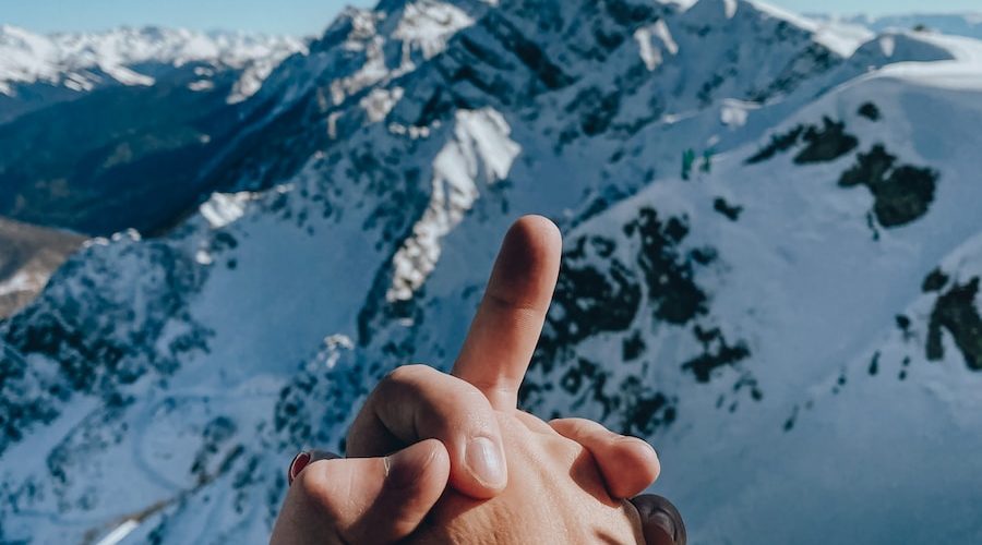 person in brown sweater showing middle finger