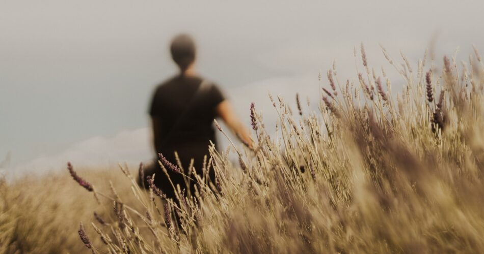 man in black shirt standing on brown grass field during daytime