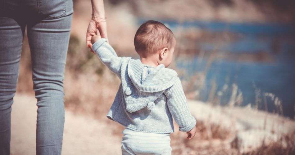 toddler's walking on the seashore with adult