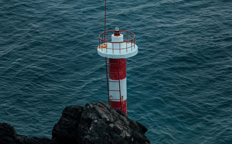 a red and white lighthouse sitting on top of a cliff